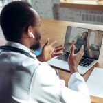 Doctor advising the patient online with laptop. African-american doctor during his videocall, work with patients, explaining recipes for drug.