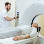 Medical technician starting MRI scan procedure of mature patient